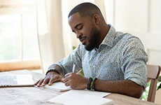 homem escrevendo textos em caderno